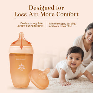 A Laad Pyaar Baby Feeding Bottle with a matching cap and detached nipple lies on a light beige floor next to a smiling baby crawling and a mother in the background. Text at the top reads 'Designed for Less Air, More Comfort' with feature callouts about dual vents and reduced gas/burping.