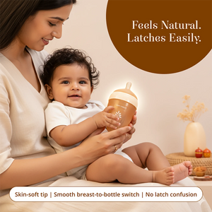 A woman holding a baby while showing the baby a Laad Pyaar Baby Feeding Bottle with a breast-like nipple. The image includes text overlays: 'Feels Natural. Latches Easily"