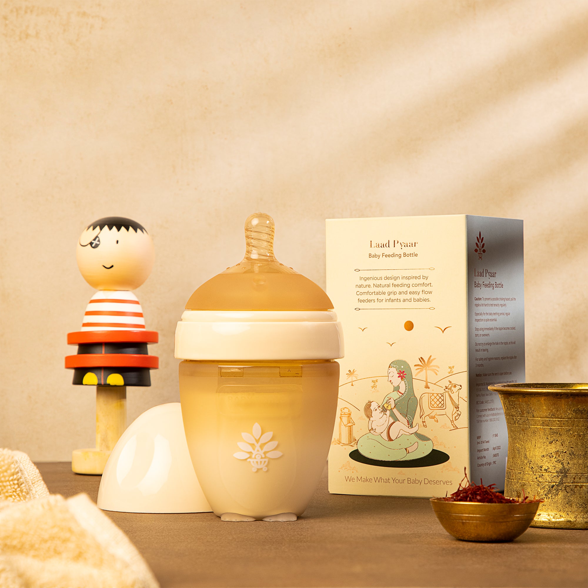 A Laad Pyaar Baby Feeding Bottle with a natural color, placed on a wooden surface, with a decorative item.