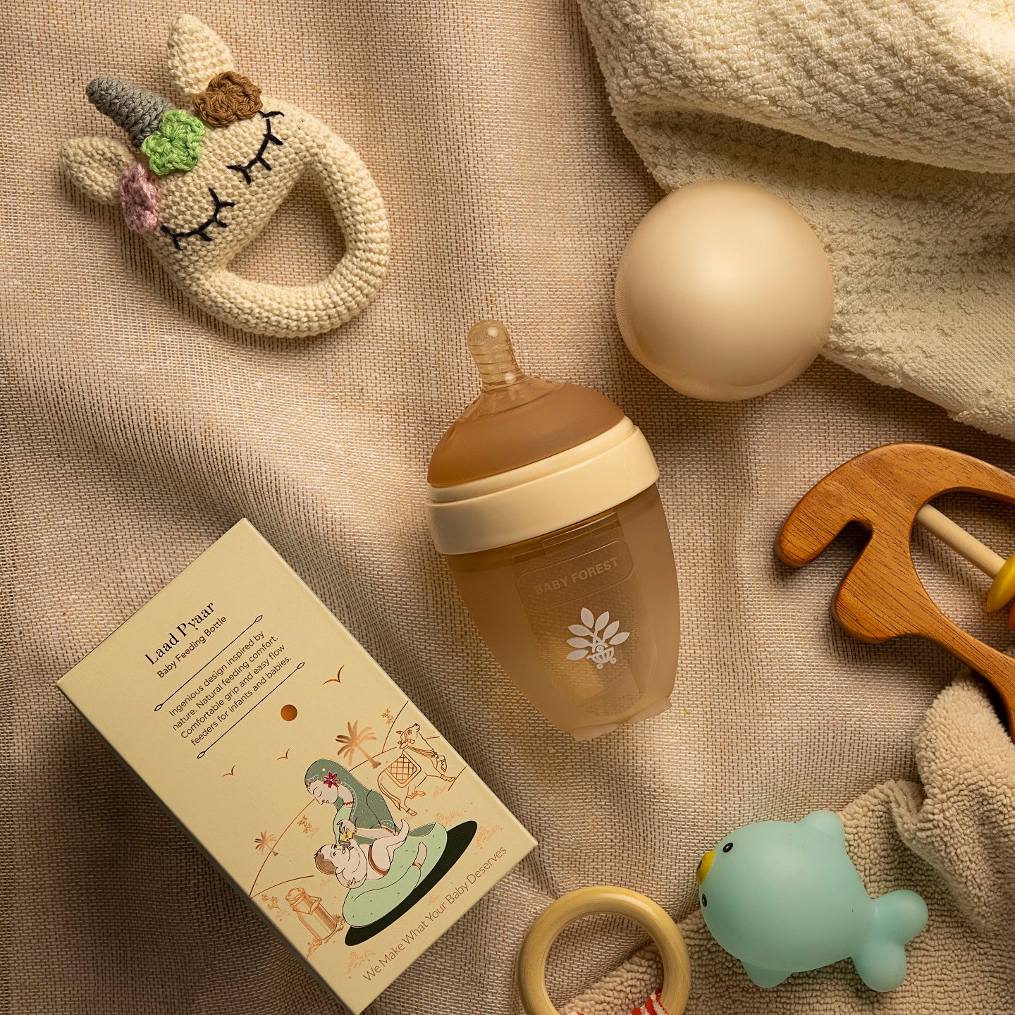 A baby feeding bottle with a natural color, placed on a wooden surface, with a decorative item.
